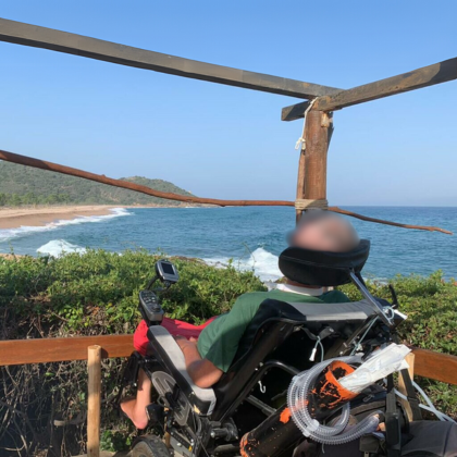 Ein Patient im Pflegerollstuhl blickt auf den Strand von Korsika